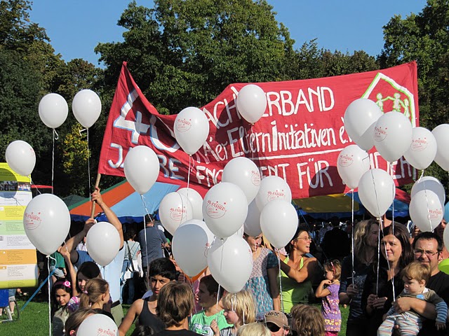 Menschen mit Luftballons und Transparent im Schlossgarten beim Dachverband Jubiläum