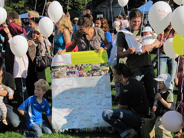 Menschen mit Luftballond und Dachverband Plakat im Schlossgarten beim Dachverband Jubiläum