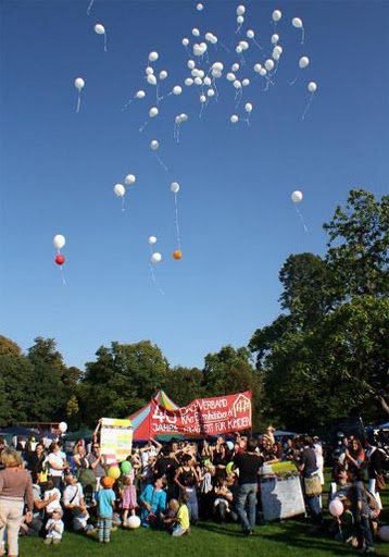 Viele Menschen mit Transparenten lassen im Schlossgraten viele Luftballons steigen